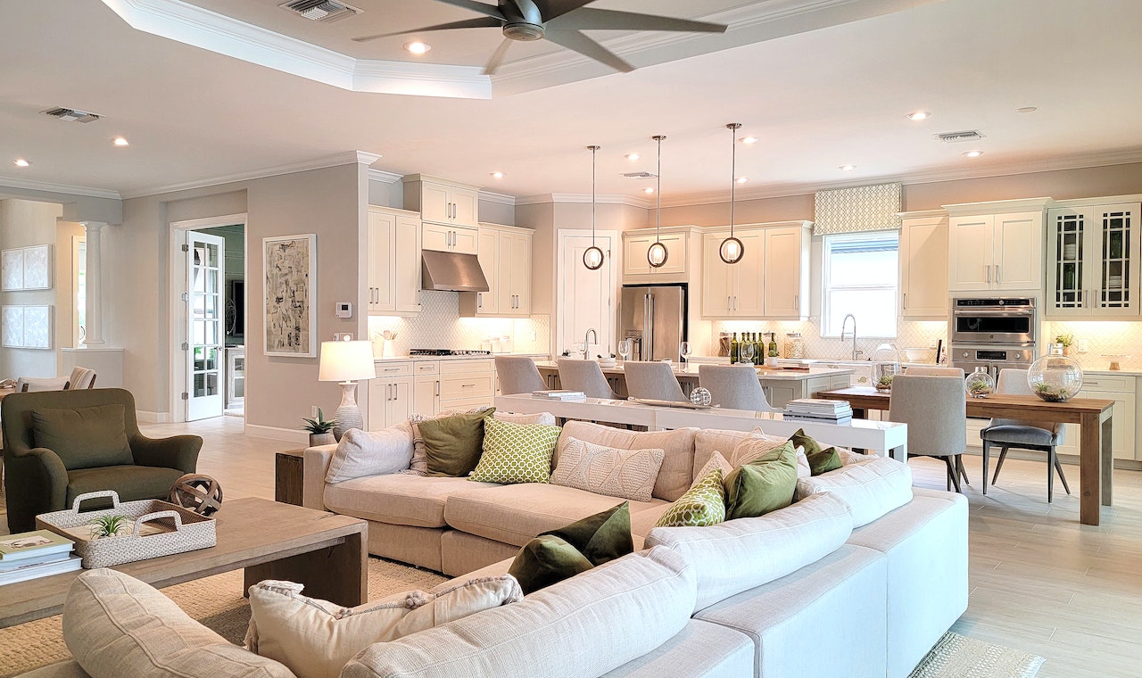 przestronny salon z widokiem na kuchnię i jadalnię, w którym króluje duży jasny narożnik.